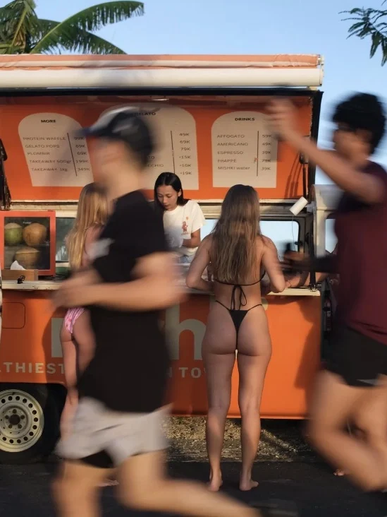 Guests ordering at the orange Mishki truck at sunset